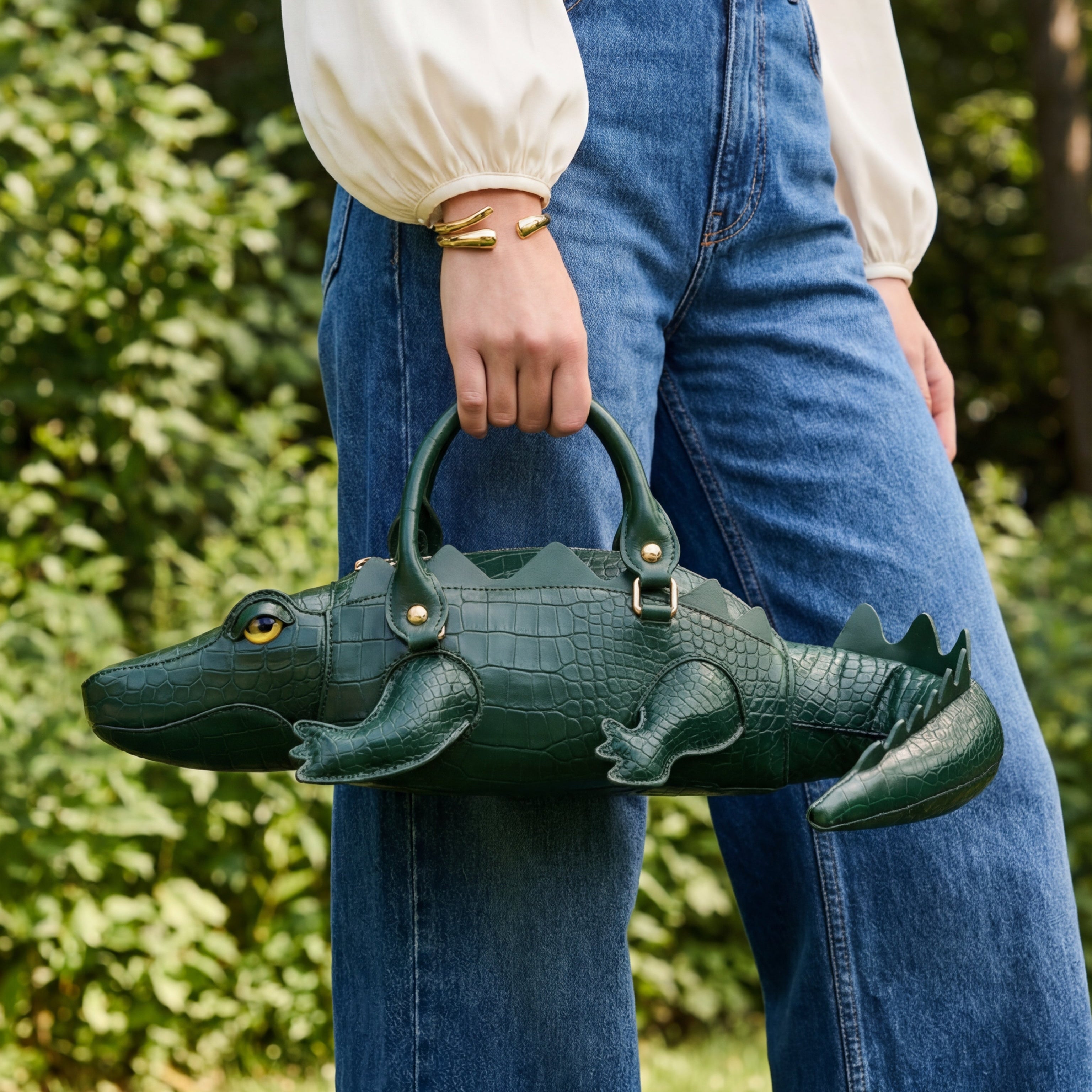 Person holding a green alligator-shaped handbag outdoors