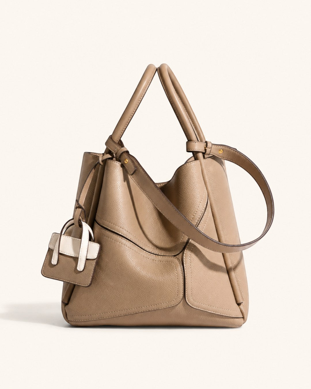 Pine Drew India Becca tote bag in beige vegan leather with gold hardware, top handles, and a detachable shoulder strap.