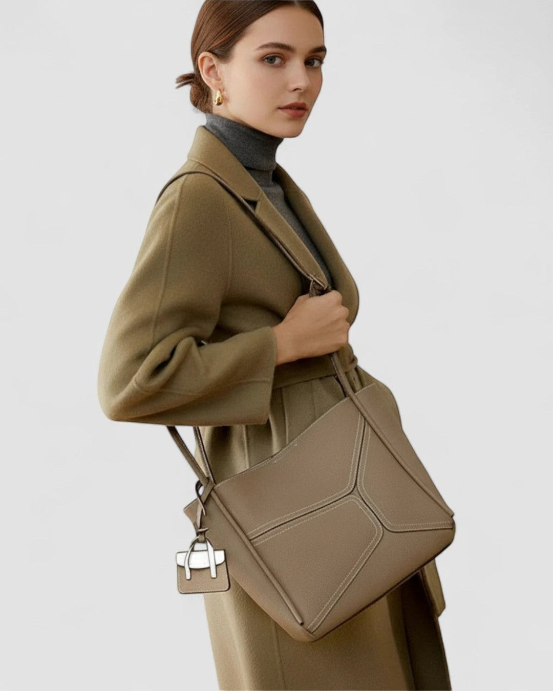Pine Drew India Becca tote bag in taupe vegan leather with gold hardware worn over the shoulder by a model