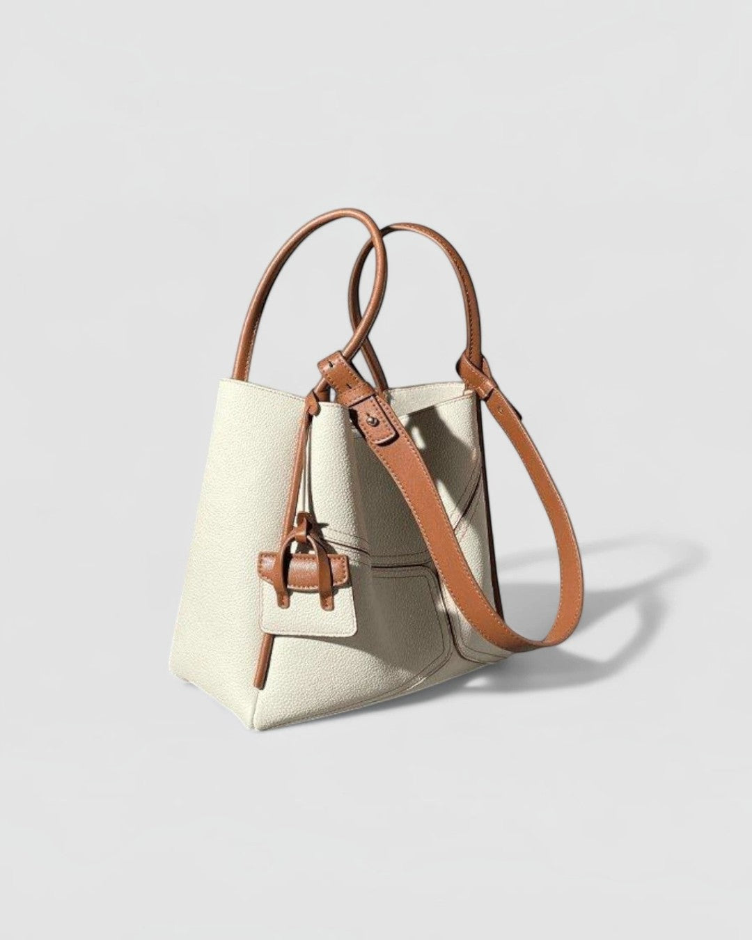 Pine Drew India Becca tote bag in cream vegan leather with tan trim, gold hardware, and adjustable shoulder strap.