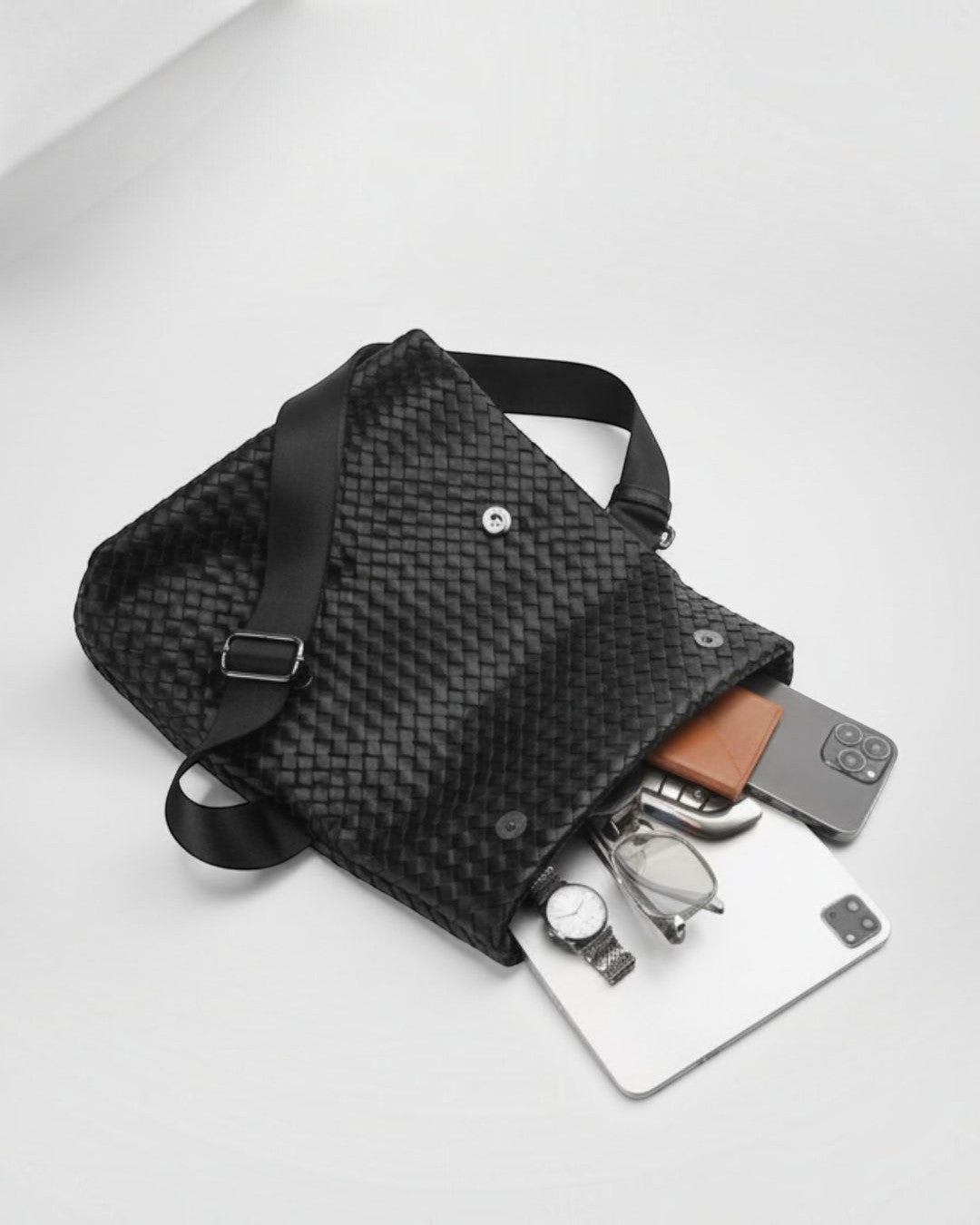 Pine Drew India black vegan leather Ravello crossbody bag with woven texture, open with daily essentials inside.
