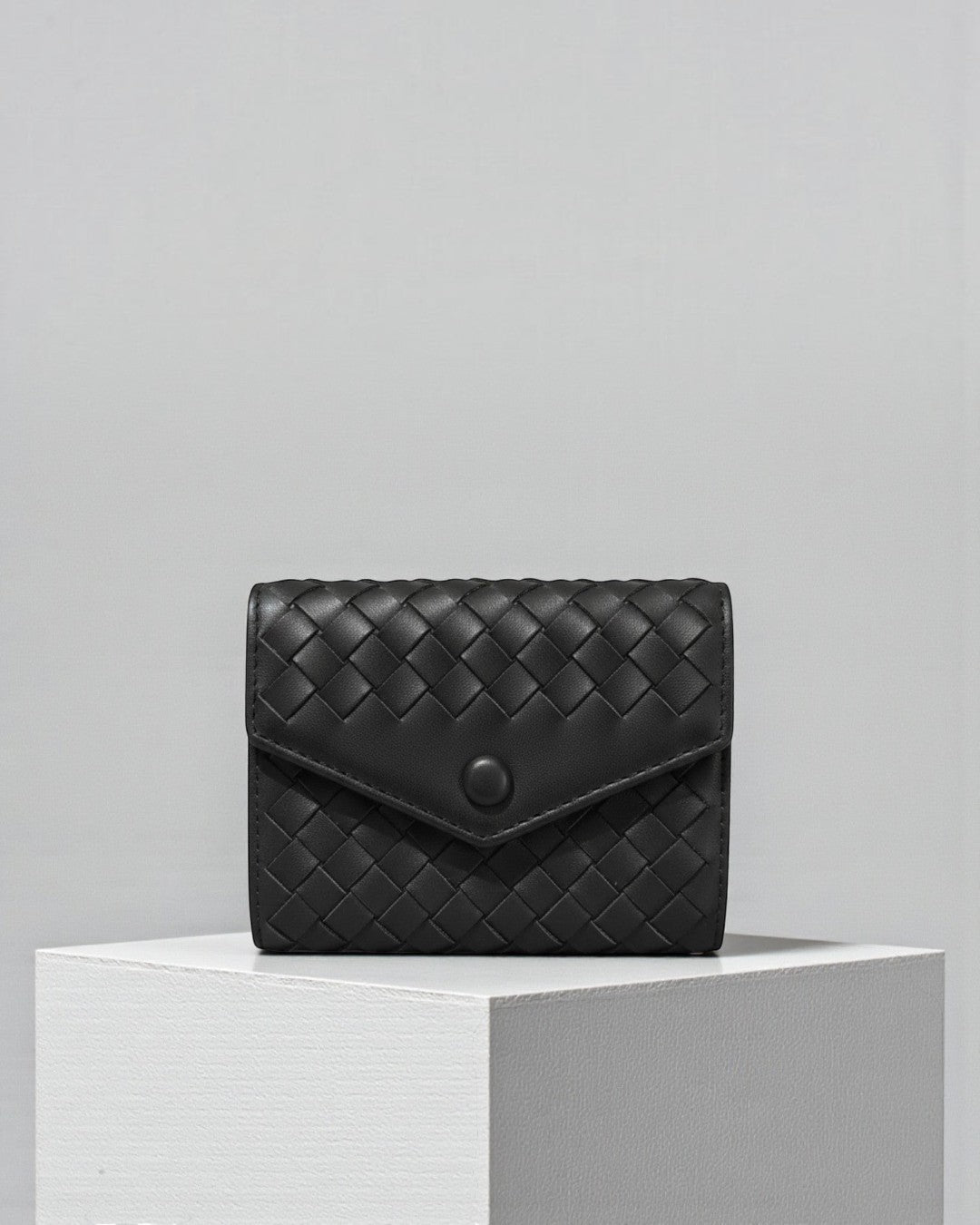 Pine Drew India Caden Interlace black leather card holder with a woven texture and matte snap closure on a white stand