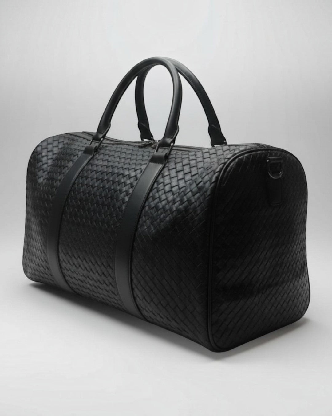 Pine Drew India Elora black vegan leather duffle bag with signature woven detailing and reinforced handles.