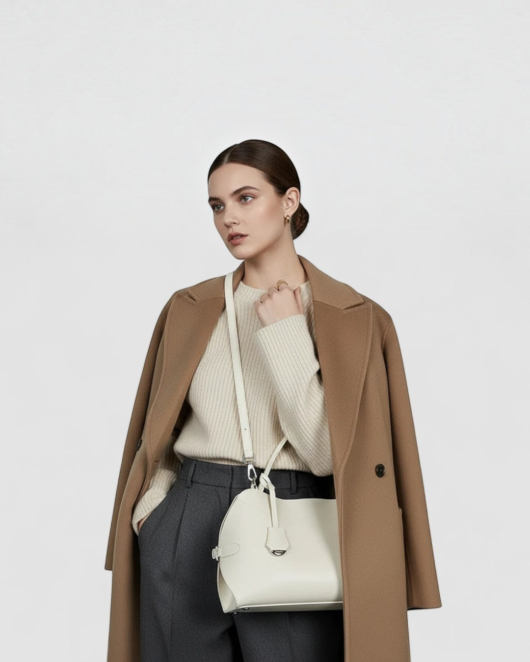 Pine Drew India Celeste white leather hobo bag worn crossbody by a model in a beige sweater and camel coat