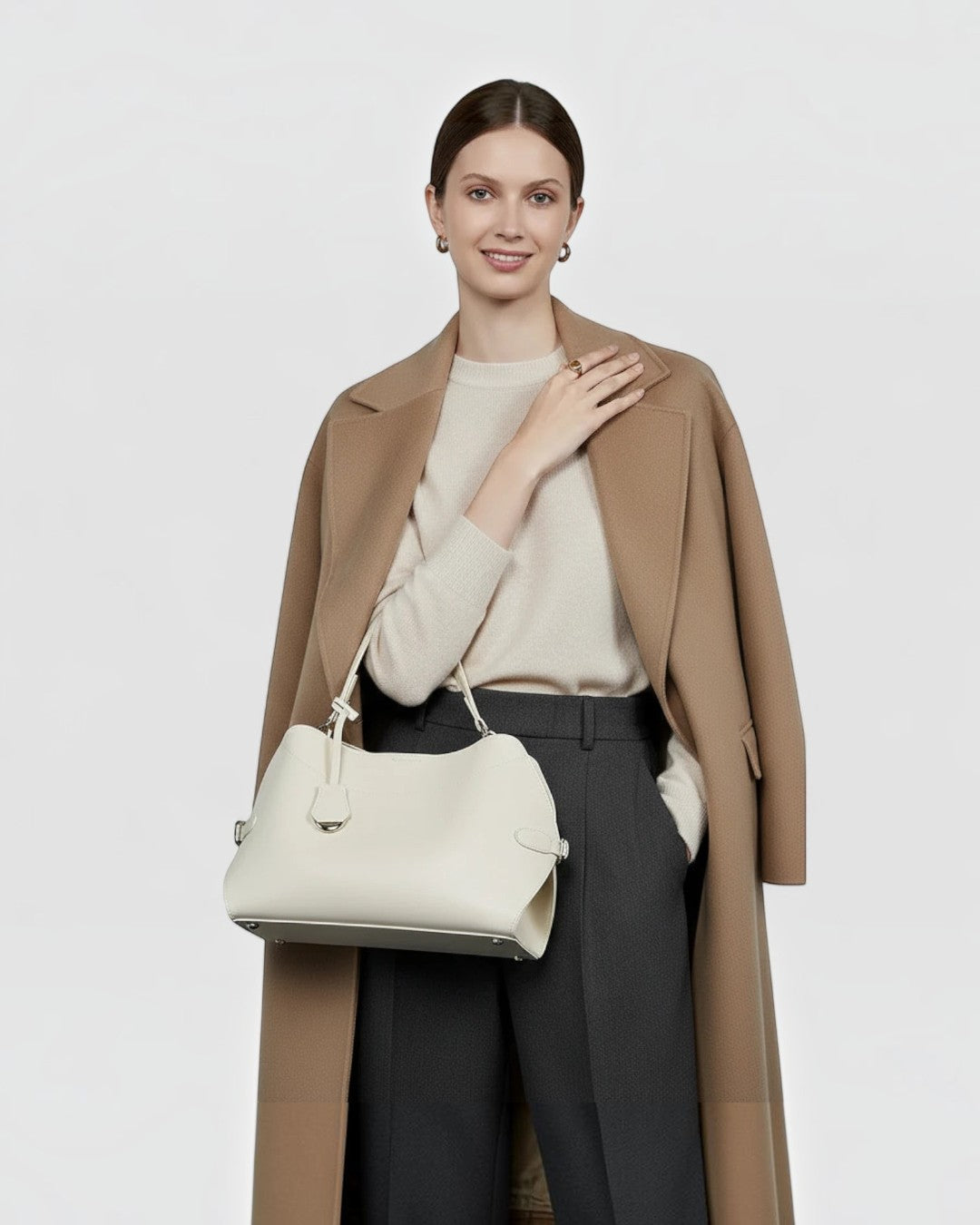 Pine Drew India Celeste hobo bag in cream leather with gold hardware, carried by a woman in a camel coat.