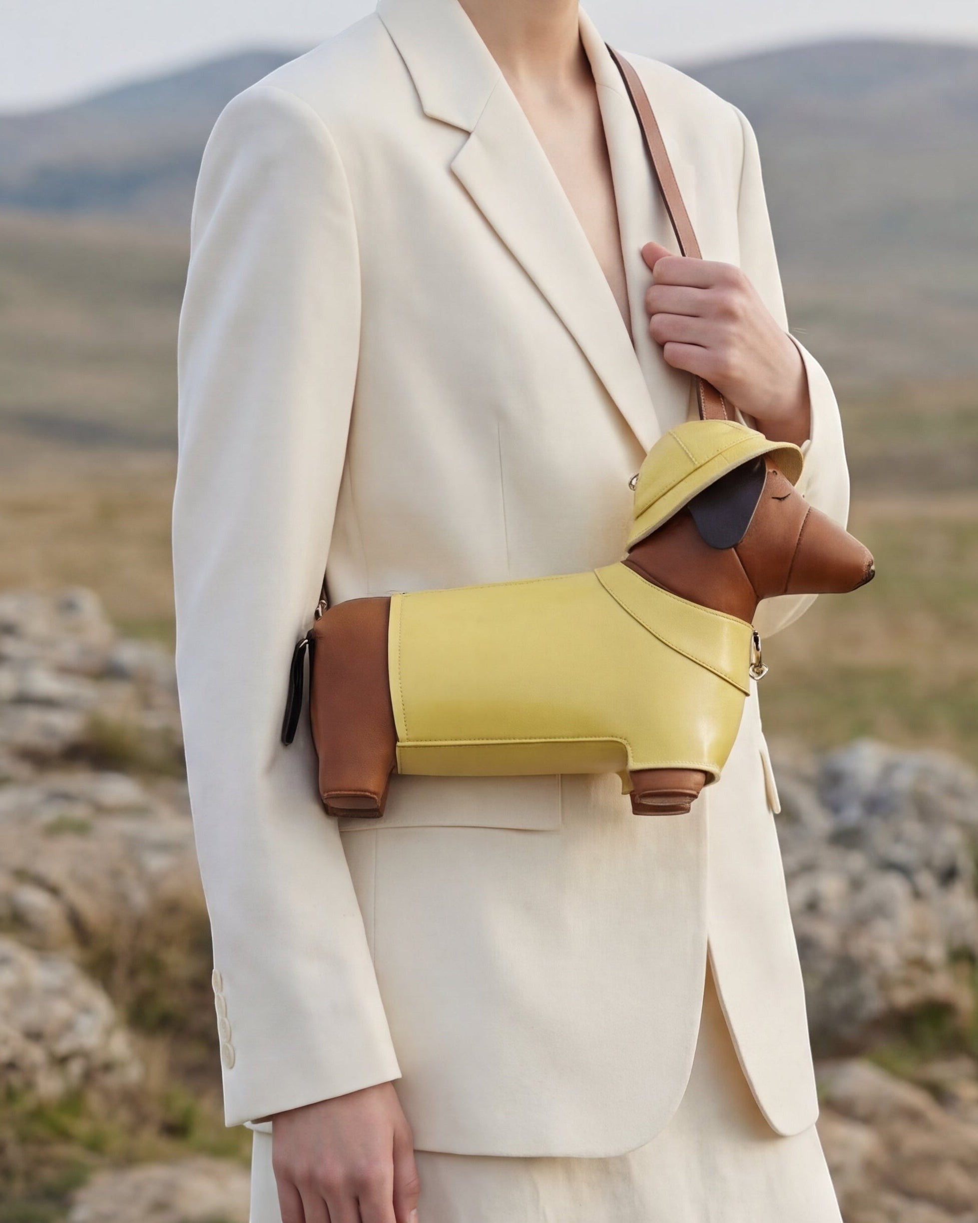 Pine Drew India dachshund shaped vegan leather bag in yellow and brown with a matching hat, worn over the shoulder.