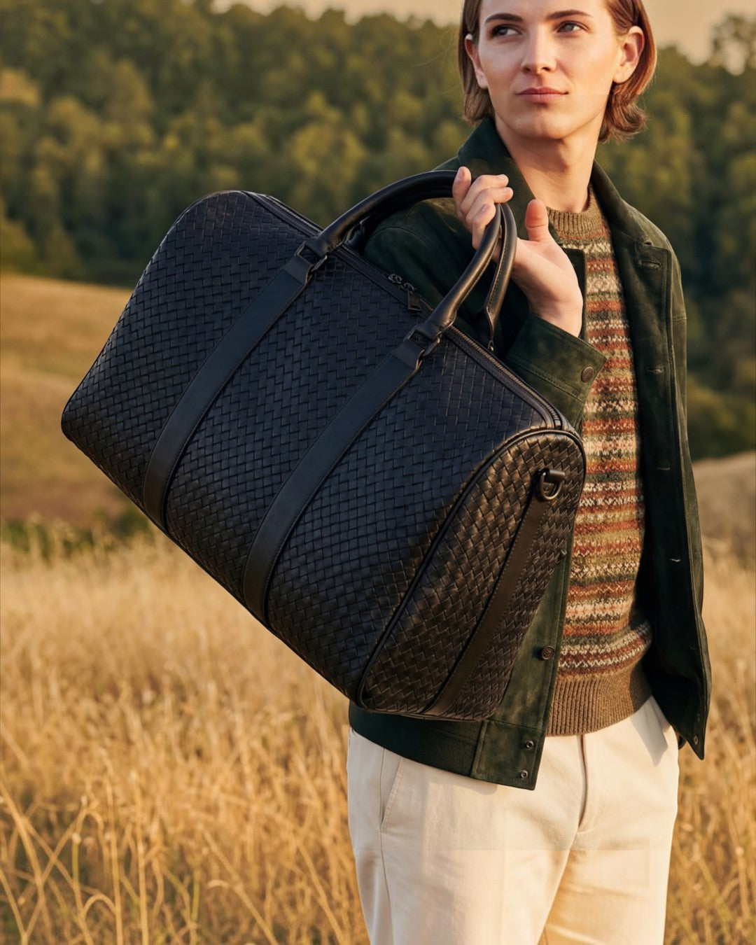 Pine Drew India Elora woven black vegan leather duffle bag carried by a person in a field at sunset