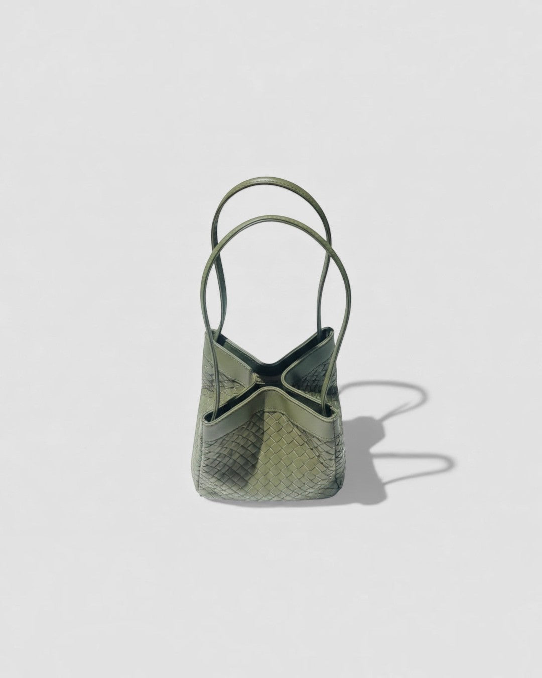 Pine Drew India Luna handbag in olive green woven leather with a structured silhouette and architectural arc handles.
