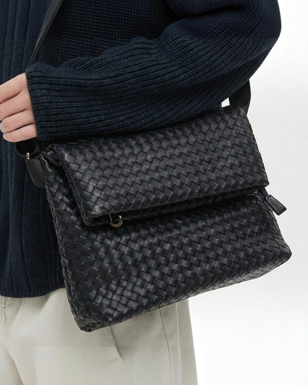 Pine Drew India Ravello black vegan leather crossbody bag with woven texture and foldover design worn on shoulder