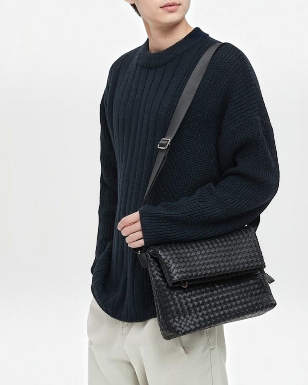 Pine Drew India Ravello black vegan leather crossbody bag with woven texture worn by a person in a dark sweater