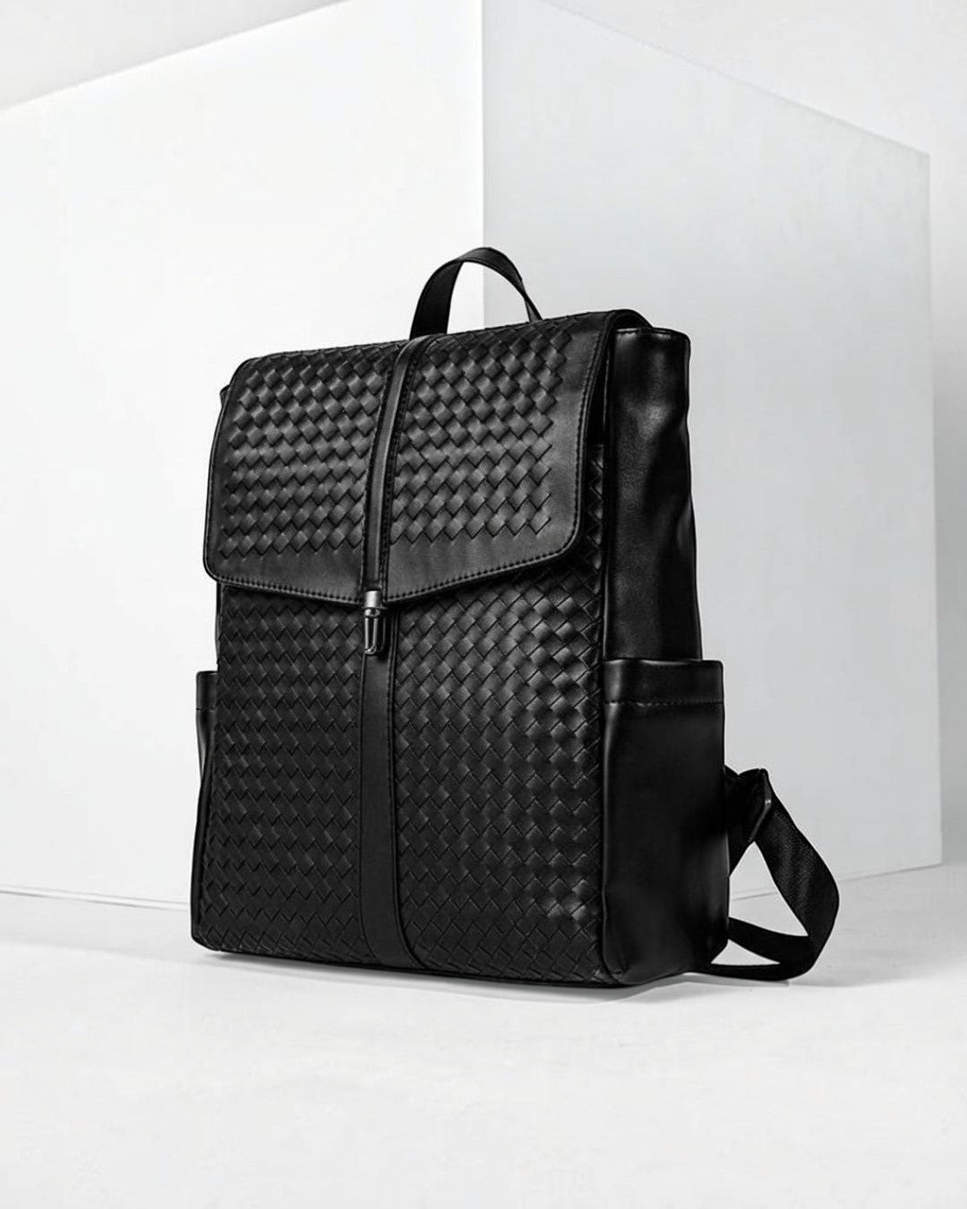 Pine Drew India Torrenzo black vegan leather backpack with a woven front panel and structured flap closure.