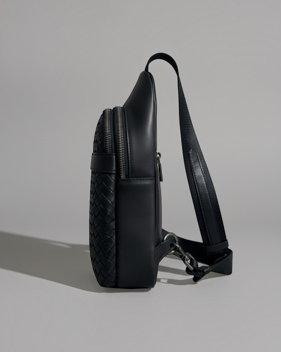 Pine Drew India Woven Voyager black full-grain leather sling bag with intricate handwoven texture and side view