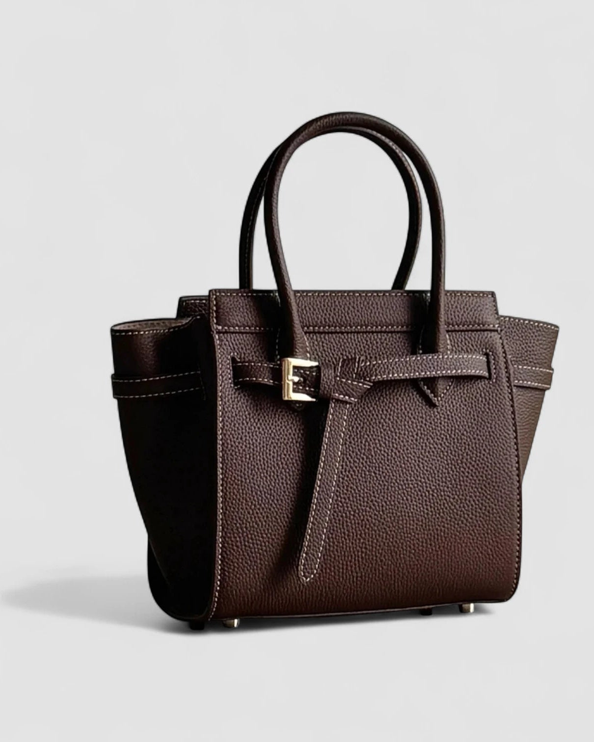 Brown leather handbag with a silver buckle on a light gray background