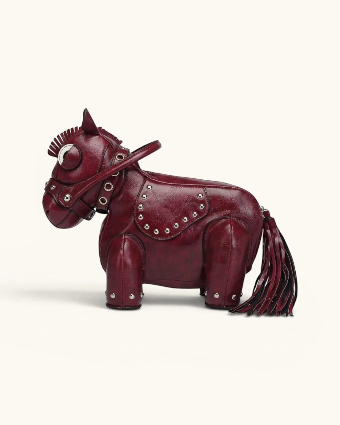 Pine Drew India Cavallo handbag in deep red vegan leather shaped like a horse with silver studs and a tassel tail.