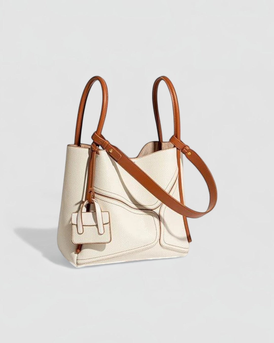 Pine Drew India Becca tote bag in cream vegan leather with tan handles and gold hardware details.