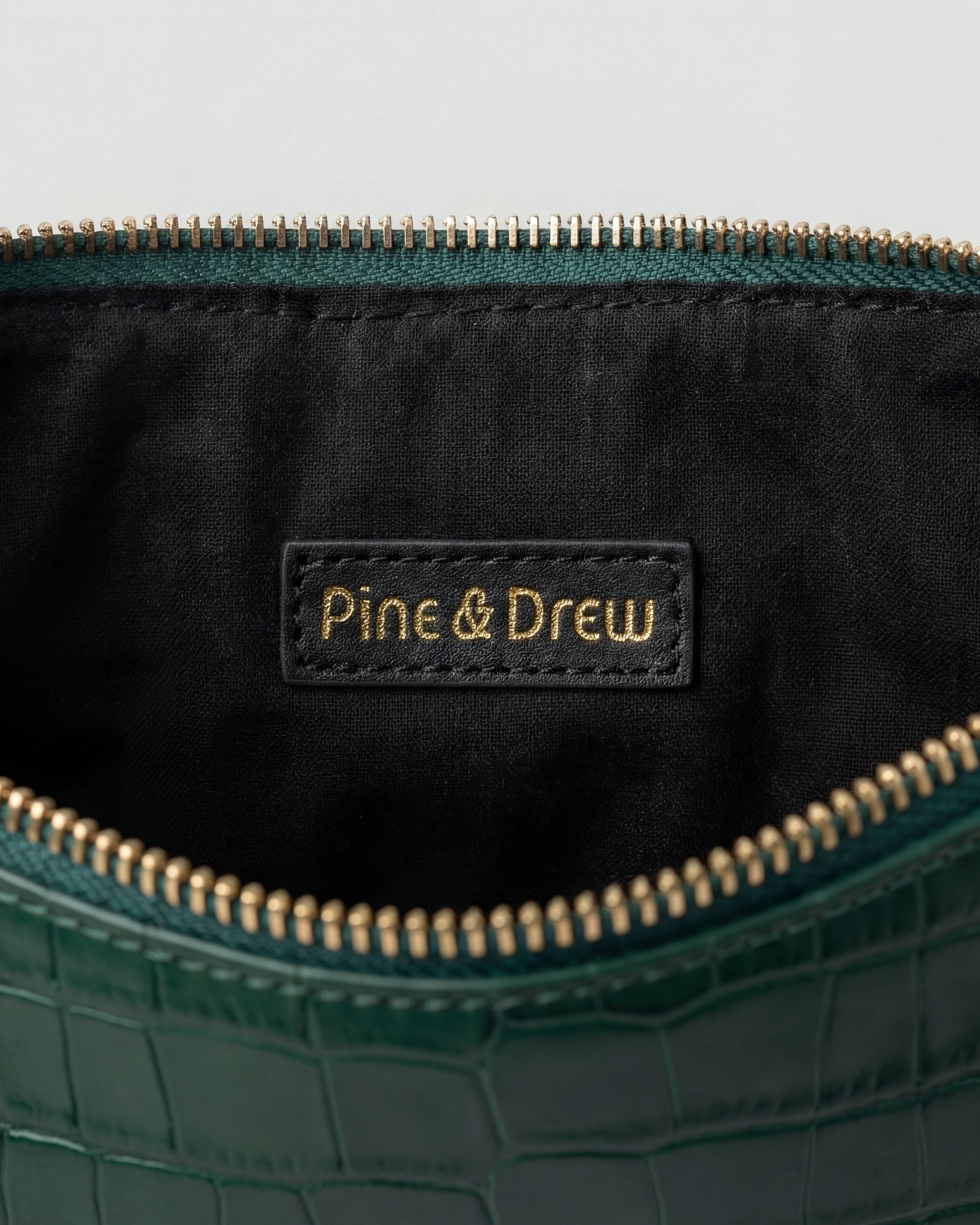 Pine Drew India Crocetta Élan mini handbag interior featuring black lining, gold zipper, and branded leather patch.