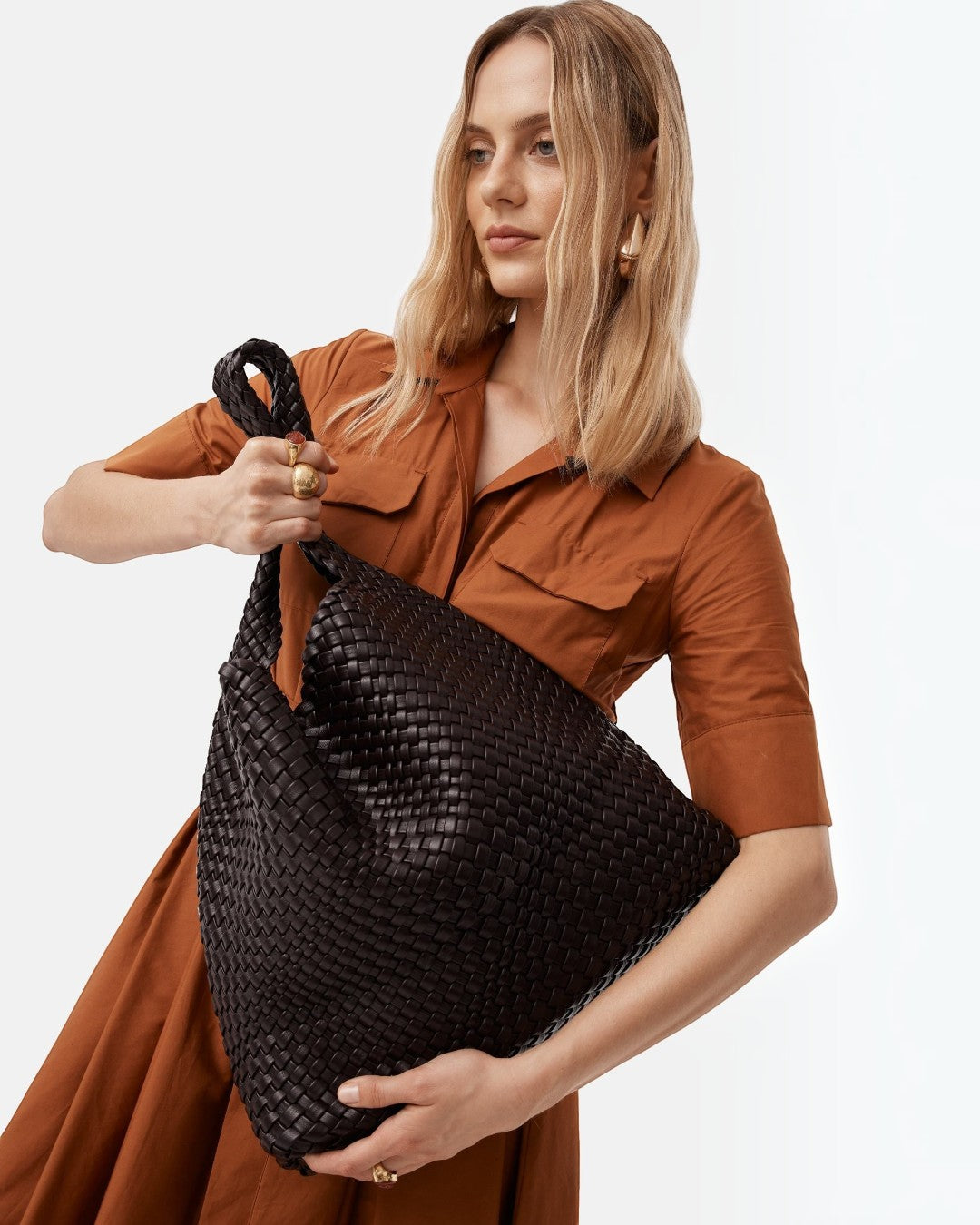 Pine Drew India Jocelyn handwoven black vegan leather slouchy shoulder bag held by a woman in a rust-colored dress