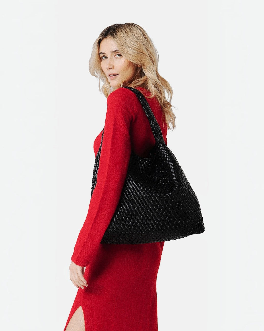 Pine Drew India Jocelyn black handwoven vegan leather shoulder bag worn by a woman in a red dress