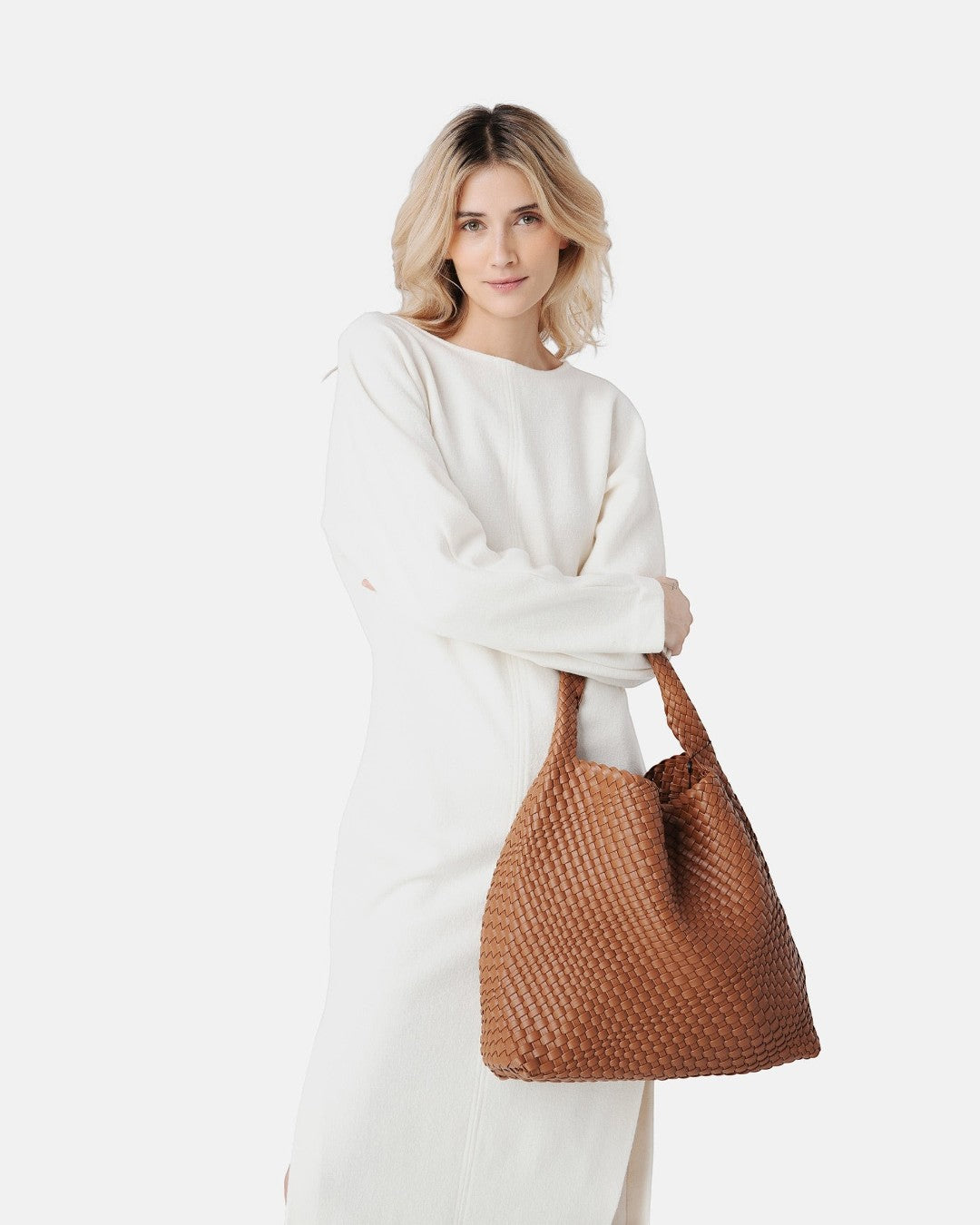 Pine Drew India Jocelyn handwoven tan vegan leather slouchy shoulder bag carried by a woman in a white dress