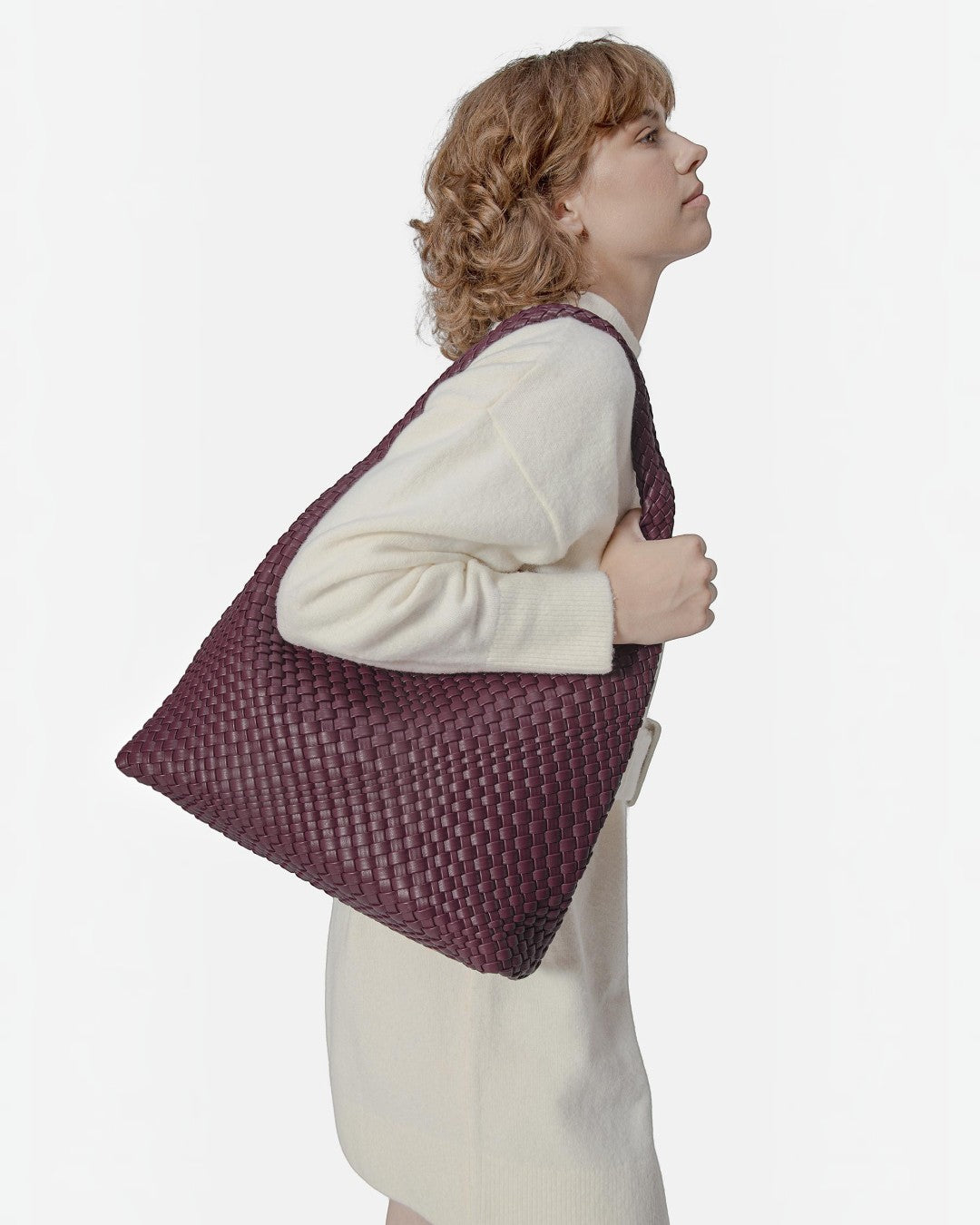 Model wearing a Pine Drew India Jocelyn handwoven deep purple vegan leather shoulder bag with a slouchy design