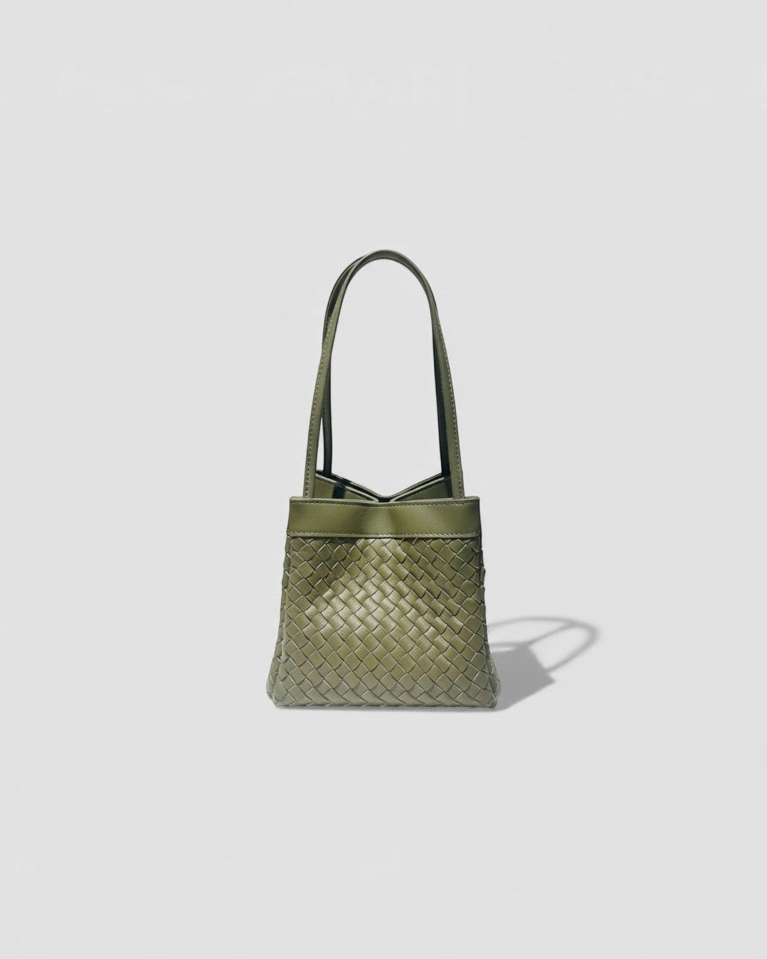 Pine Drew India Luna handbag in olive green full-grain leather with an intricate handwoven exterior and arc handles.