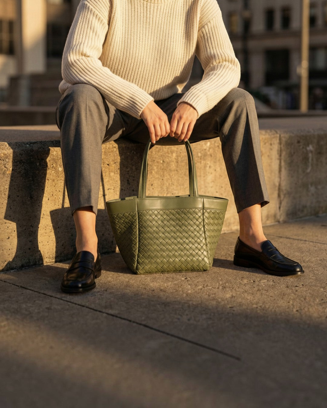 Pine Drew India Luna Verdura olive green woven leather handbag with structured silhouette held by a person in knitwear