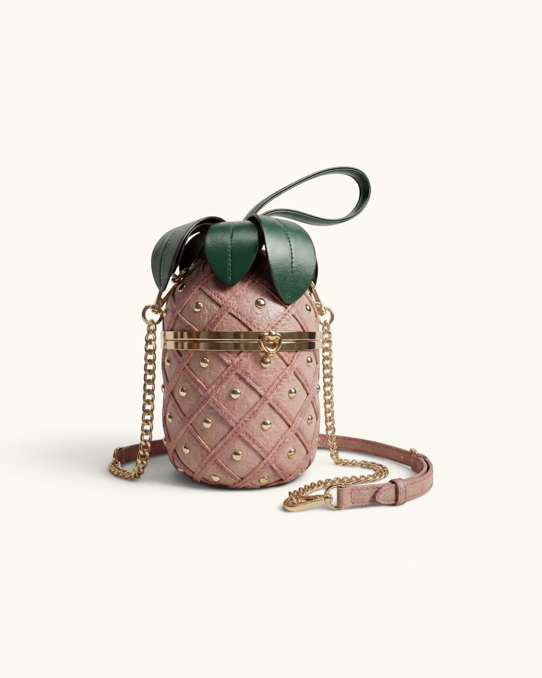 Pine Drew India pineapple-shaped vegan leather clutch in pink with gold studs, green leaf crown, and gold chain strap.