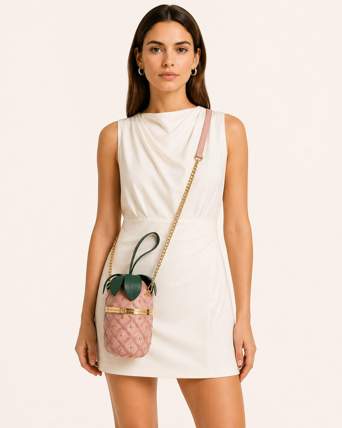 Pine Drew India Palmiera pineapple-shaped vegan leather clutch in pink with gold studs and green leaf crown.