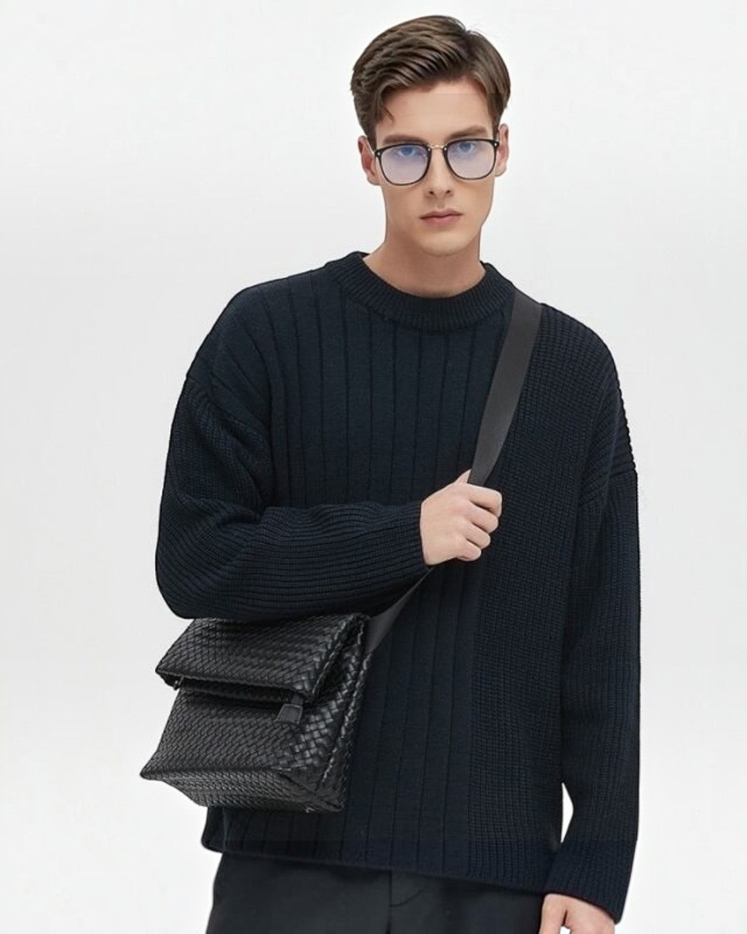 Pine Drew India Ravello black vegan leather foldover crossbody bag with woven texture worn by a man in a sweater.