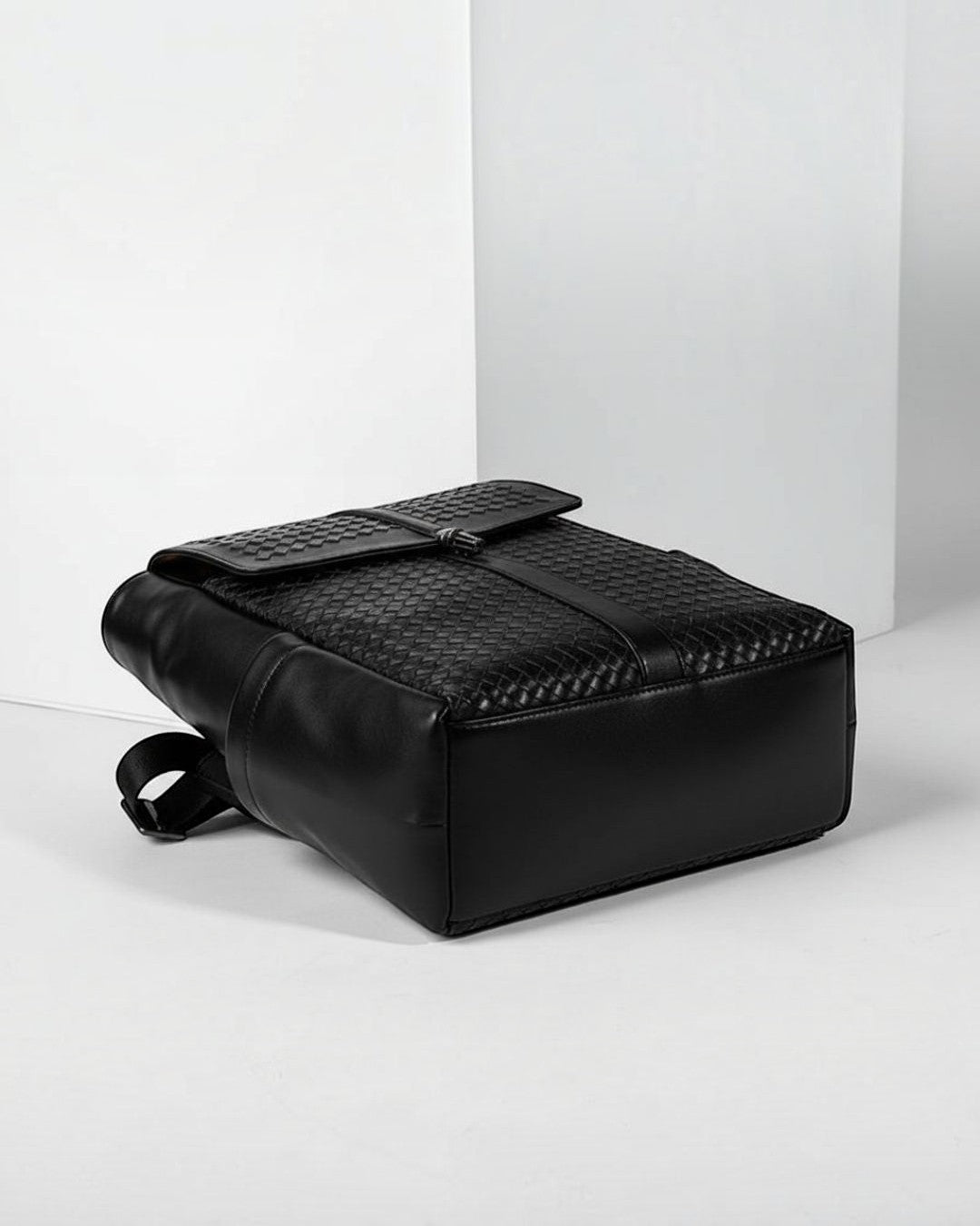 Pine Drew India Torrenzo black vegan leather backpack with a woven front panel and structured flap closure.