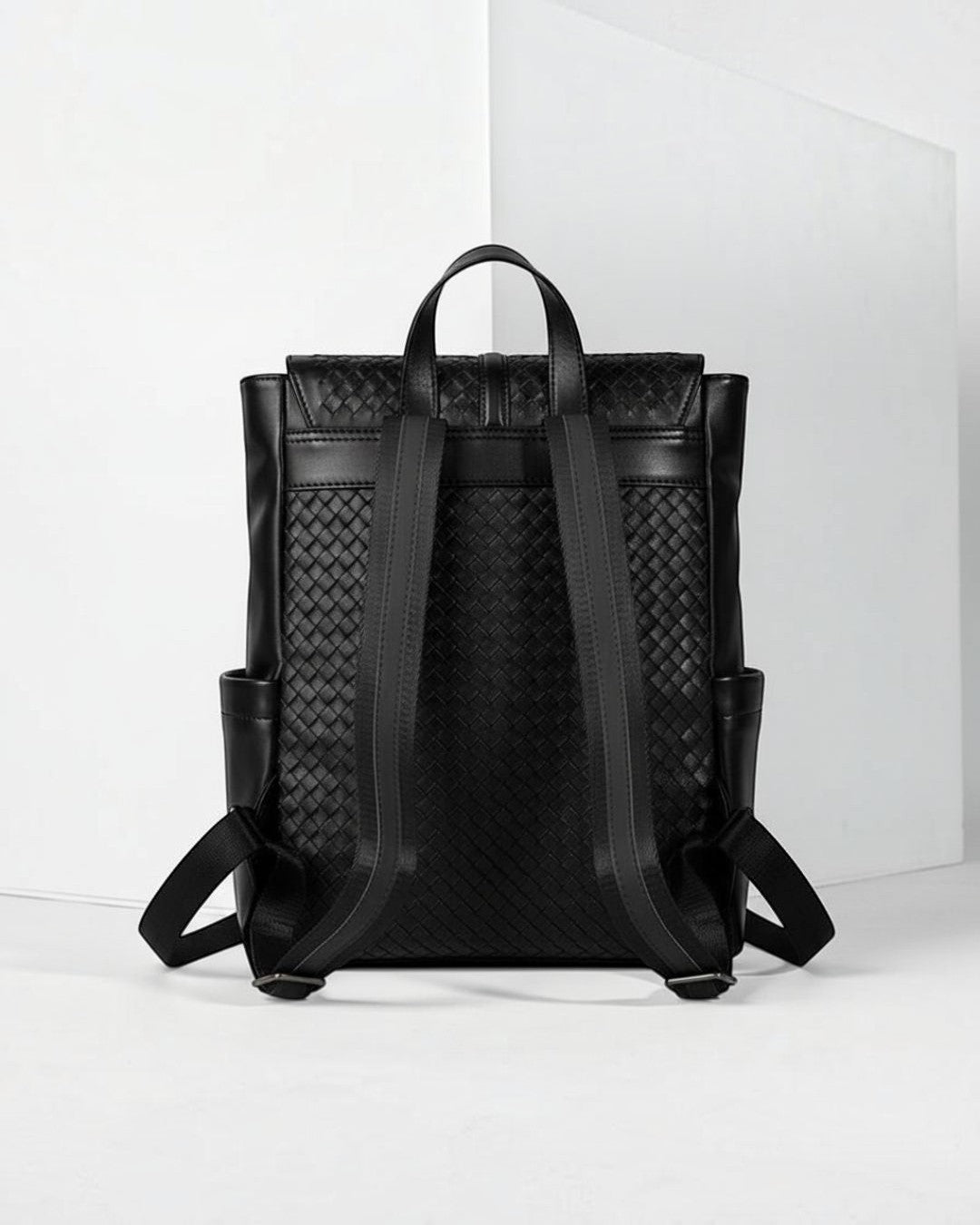 Pine Drew India Torrenzo black vegan leather backpack with a woven grid pattern, padded straps, and side pockets.