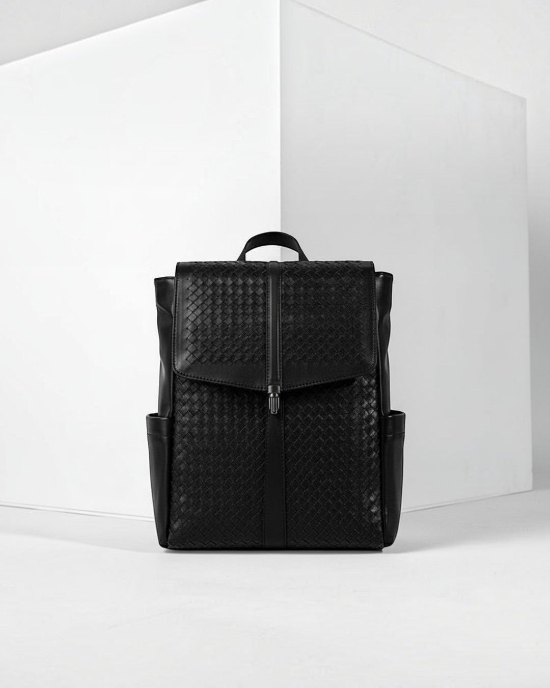 Pine Drew India Torrenzo black vegan leather backpack with a woven front panel and structured flap closure.