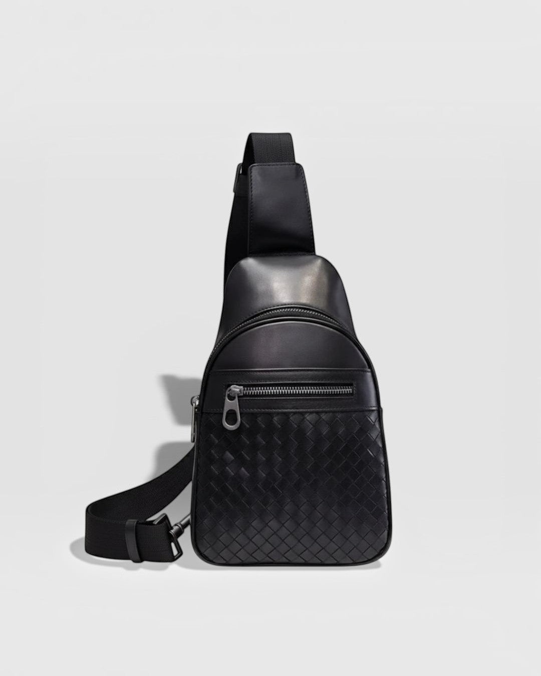 Pine Drew India Woven Voyager black full-grain leather sling bag with intricate handwoven texture and zipper pocket.